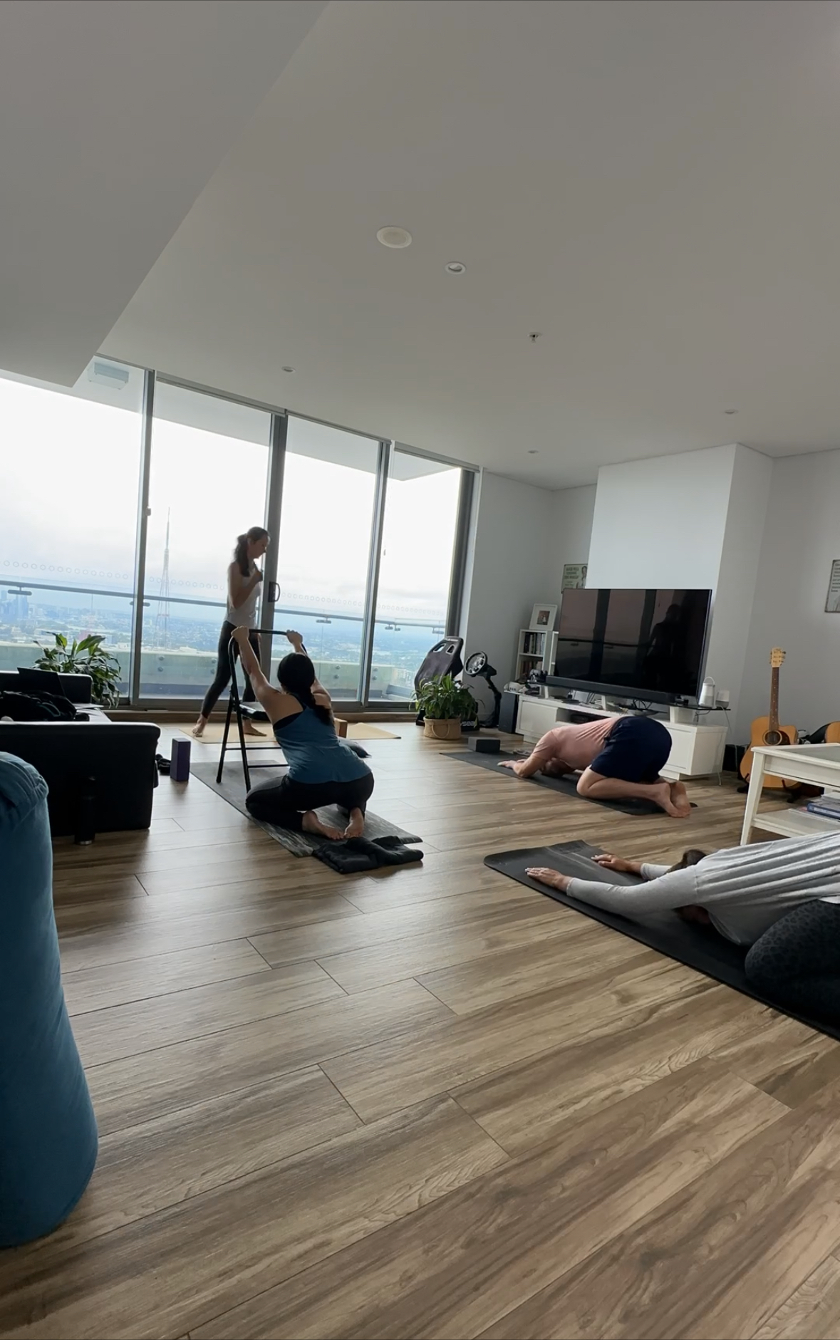 Three people practising guided rhythmic movement with yoga blocks in a bright studio overlooking the landscape